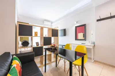 a living room with a black table and yellow chairs at Let me Athens you! in Athens