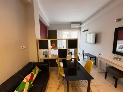 a living room with a black couch and a table at Let me Athens you! in Athens
