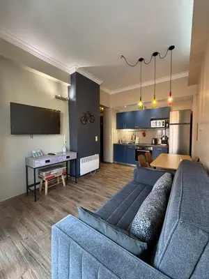 a living room with a blue couch and a kitchen at Let me Athens you! #2 in Athens