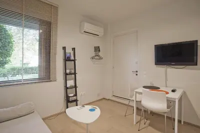 a white living room with a table and chairs at Cozy and modern studio next to the sea in Athens