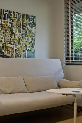 a couch in a living room with a painting on the wall at Cozy and modern studio next to the sea in Athens