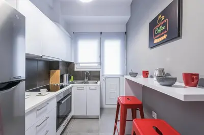 a kitchen with white cabinets and a red stool at Elegant living at the heart of Athens in Athens