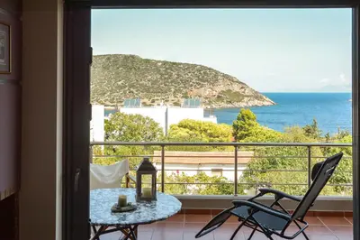 a view of the ocean from a balcony with a table and chairs at Serenity Villa-1st floor-Panoramic Sea view- sea 150m away in Porto Rafti