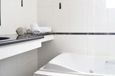 a white bathroom with a tub and a sink at Poseidon by Heloni Apartments in Piraeus
