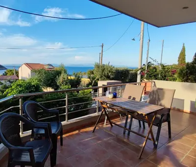a patio with a wooden table and chairs on a balcony at Serenity Villa-Ground floor-Sea view- sea 150m away in Porto Rafti