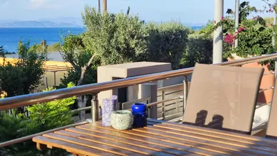 a wooden bench on a balcony with a view of the ocean at Serenity Villa-Ground floor-Sea view- sea 150m away in Porto Rafti