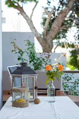 a table with a lantern and a vase with orange flowers at Serenity Villa-Ground floor-Sea view- sea 150m away in Porto Rafti