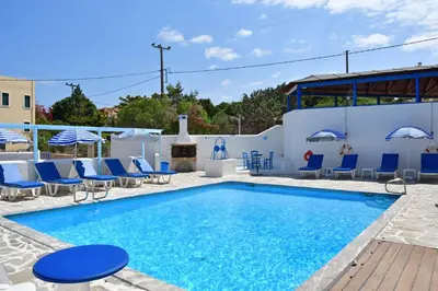a swimming pool with blue chairs and a fire place at Blue Dolphin Studios and Apartment in Vaia