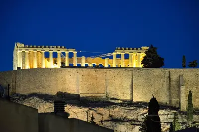 a view of a building behind a wall at night at Acropolis amazing balcony view 3 minutes walking to the museum in Athens