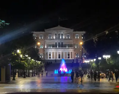 a building with a fountain in front of it at night at Acropolis area 5 minutes to the Museum and metro in Athens
