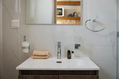 a bathroom with a white sink and a mirror at Acropolis Sandra Homes in Athens