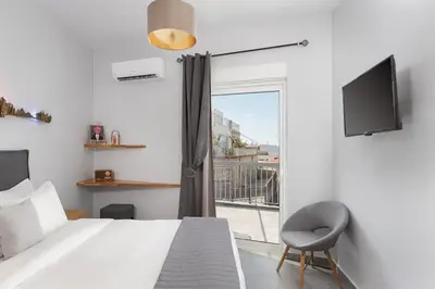 a bedroom with a bed and a tv and a window at Acropolis Sandra Homes in Athens