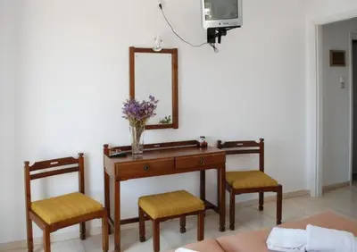 a desk with two chairs and a vase of flowers on it at Hotel 3 Adelfia in Agia Marina Aegina