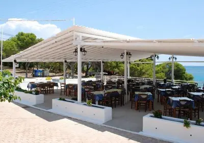 a restaurant with tables and chairs under a white canopy at Hotel 3 Adelfia in Agia Marina Aegina