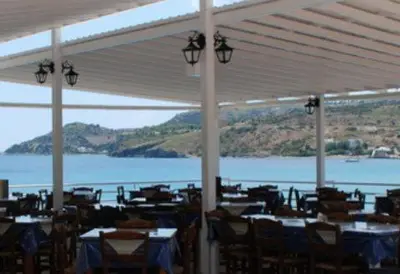 a restaurant with tables and chairs and a view of the water at Hotel 3 Adelfia in Agia Marina Aegina