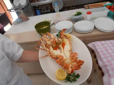 a person holding a plate with a lobster on it at Hotel 3 Adelfia in Agia Marina Aegina