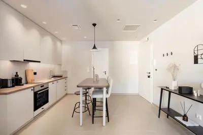 a kitchen with white cabinets and a table in it at Luxury Apartments in Plaka by UPSTREET in Athens