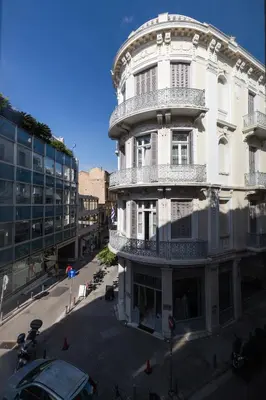 a white building with a balcony on a street at Luxury Apartments in Plaka by UPSTREET in Athens