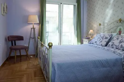 a bedroom with a bed with a blue comforter and a window at THE HOUSE OF LAVENDER in Athens