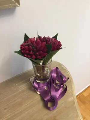 a vase of red flowers on a table with a purple ribbon at THE HOUSE OF LAVENDER in Athens