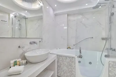 a white bathroom with a tub and a sink at Ava Hotel and Suites in Athens