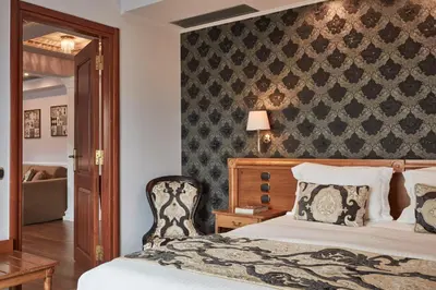 a bedroom with a bed and a chair and a wall at Ava Hotel and Suites in Athens