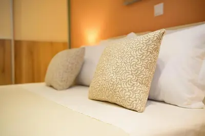 a bed with white pillows and a tan and white pillow at Alimos Modern Retreat, near the beach in Athens