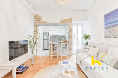 a living room with a white couch and a kitchen at Lush island-style hideaway in lively Koukaki! in Athens
