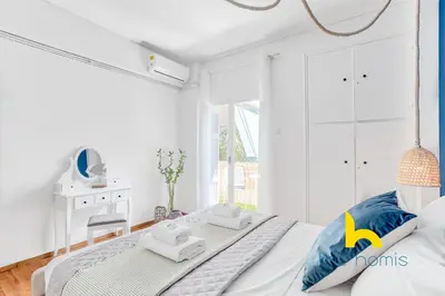 a white bedroom with a bed and a desk at Lush island-style hideaway in lively Koukaki! in Athens