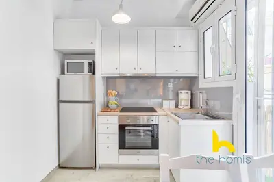 a kitchen with white cabinets and a white refrigerator at Lush island-style hideaway in lively Koukaki! in Athens