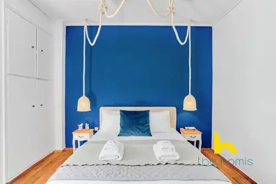a blue bedroom with a bed with two towels on it at Lush island-style hideaway in lively Koukaki! in Athens