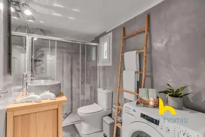 a bathroom with a washing machine and a toilet at Lush island-style hideaway in lively Koukaki! in Athens
