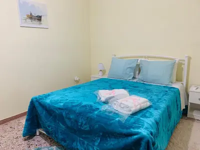 a bedroom with a blue bed with two pillows at Small Apartment in Markopoulo center in Markopoulo