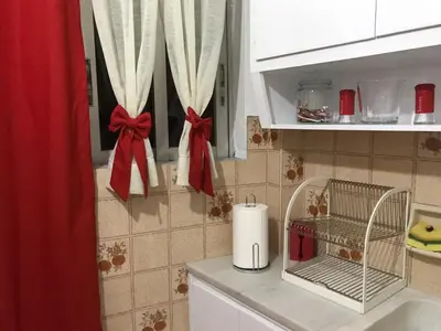 a kitchen with white cabinets with bows on the counters at Small Apartment in Markopoulo center in Markopoulo