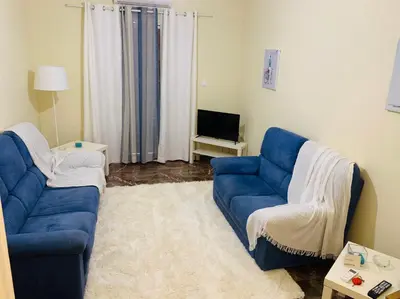 a living room with two blue couches and a television at Small Apartment in Markopoulo center in Markopoulo