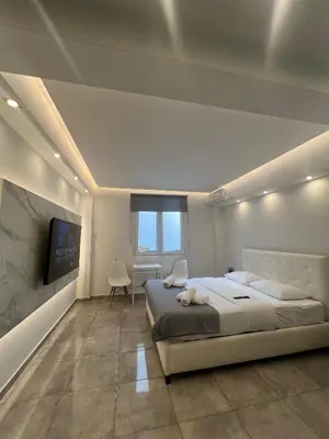a bedroom with a large bed and a flat screen tv at Purple- Lux studio 2' from metro Petralona in Athens