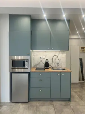 a kitchen with blue cabinets and a microwave at Purple- Lux studio 2' from metro Petralona in Athens