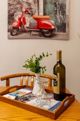 a wooden table with a bottle of wine and a vase at Comfortable garden Apt near Vouliagmeni beach in Athens