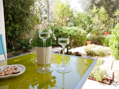 a table with two wine glasses and a plate of donuts at Comfortable garden Apt near Vouliagmeni beach in Athens