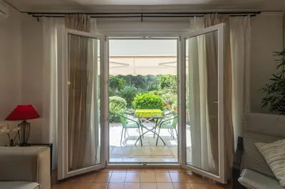 a sliding glass door leading to a patio with a table at Comfortable garden Apt near Vouliagmeni beach in Athens