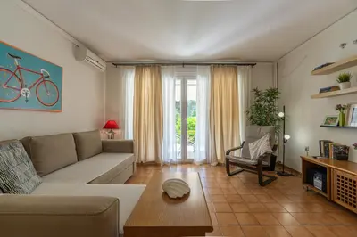 a living room with a couch and a table at Comfortable garden Apt near Vouliagmeni beach in Athens