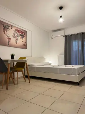 a bedroom with a bed and a table and a table and chair at Jacuzzi studio close to athens airport!! in Pallíni