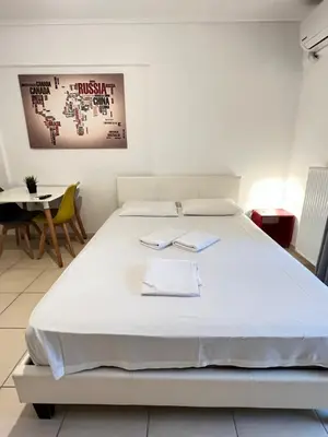 a bedroom with a large white bed and a table at Jacuzzi studio close to athens airport!! in Pallíni
