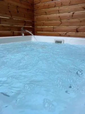 a bath tub filled with blue water next to a wooden wall at Jacuzzi studio close to athens airport!! in Pallíni
