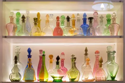 a shelf filled with lots of different colored glass bottles at 