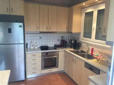 a kitchen with wooden cabinets and a stainless steel refrigerator at Relaxing Villa with Swimming Pool and Garden in Áyios Yeóryios