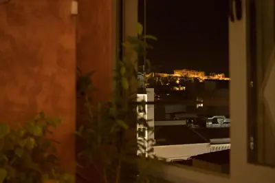 a view of a city at night from a window at Mosaics aprtm in the historical center of Athens Ermou 18 in Athens