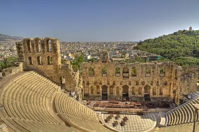 an ancient amphitheater with a city in the background at Boho House with Acropolis View! in Athens
