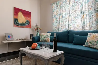 a living room with a blue couch and a table with wine glasses at Athens Flower Apartment in Athens
