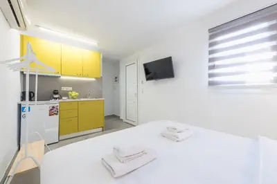 a white room with a kitchen with yellow cabinets at Athens Oasis in Athens